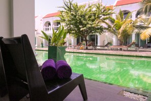 Ein Poolbereich mit Liegestuhl, Topfpflanze und Schwimmbecken.