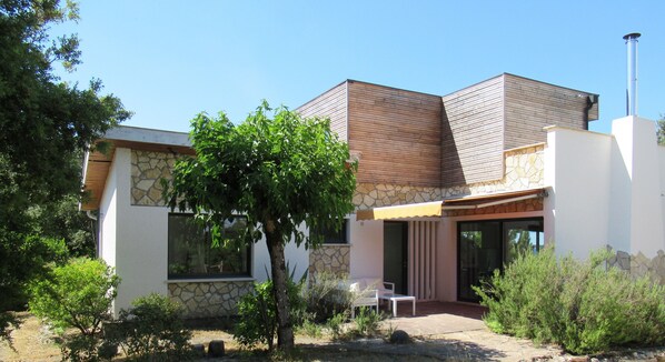 A modern house with a stone facade, a wooden upper section, and a large glass door.