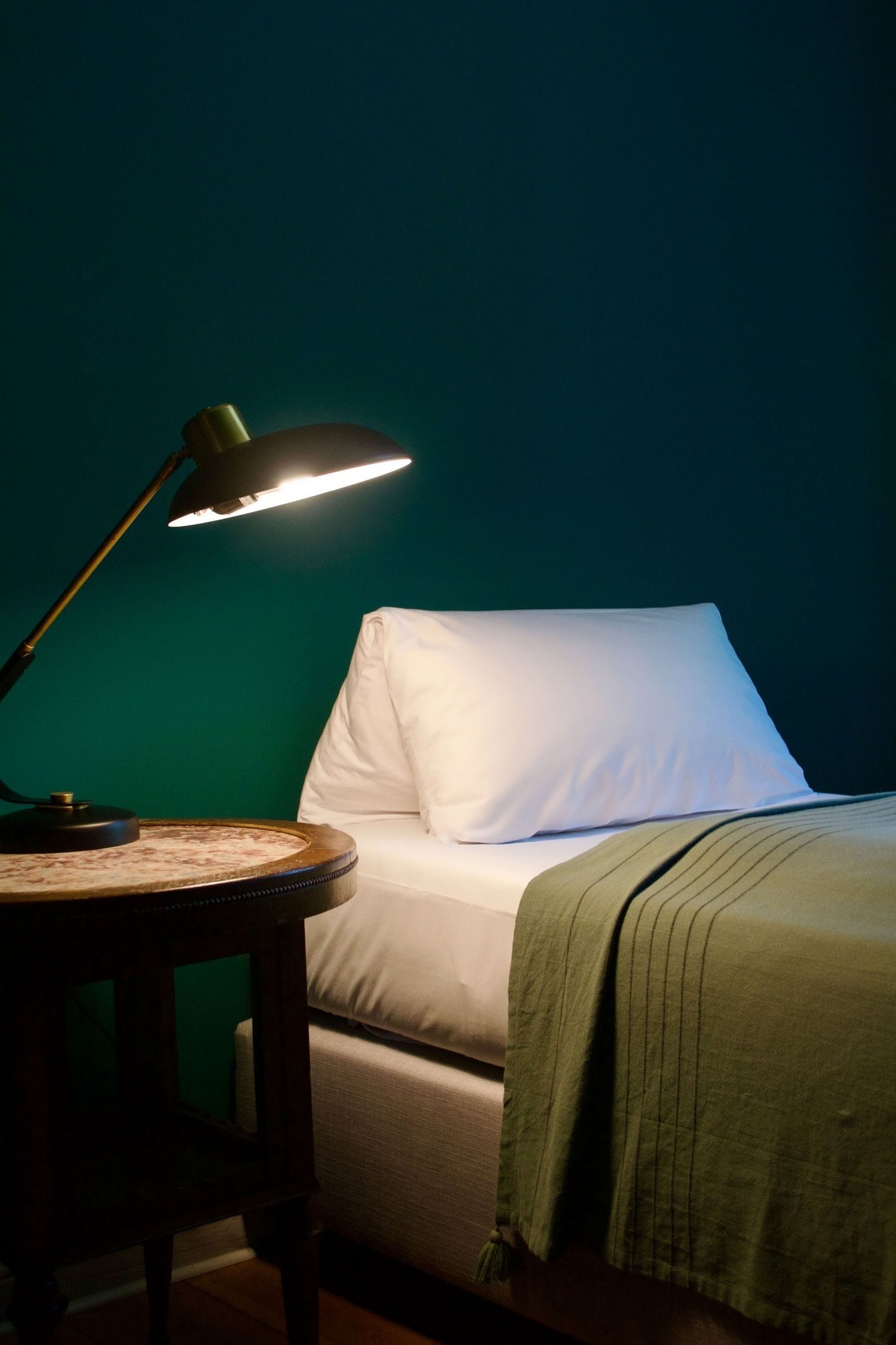 A room with a bed, a bedside table, and a lamp.