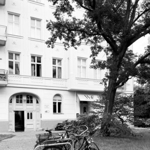 A building with a large tree in front, multiple windows, and a sign that reads "BOUTIQUE HOTEL".