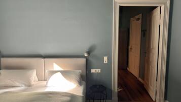 Quarto com cama, abajur e um banquinho.