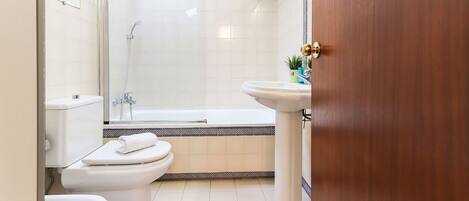 Un baño con inodoro, lavamanos y zona de ducha.