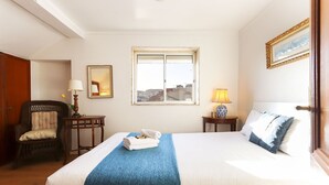 A hotel room with a large bed, a chair, a desk, and a window with a city view. - Downtown Experience By Homing (Lisbon)