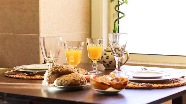 A breakfast setting with a table set for two, including plates, glasses, and a variety of pastries. - Downtown Experience By Homing (Lisbon)