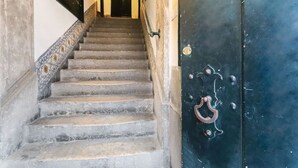 A staircase leading to a dark door with a brass handle and a lock. - Downtown Experience By Homing (Lisbon)