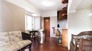 A compact living space with a sofa, dining table, and kitchen area. - Downtown Experience By Homing (Lisbon)
