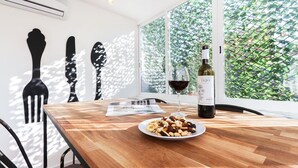 A dining table with a plate of nuts and a wine bottle, a glass of red wine, and a menu. - Rato Design With Terrace By Homing (Lisbon)