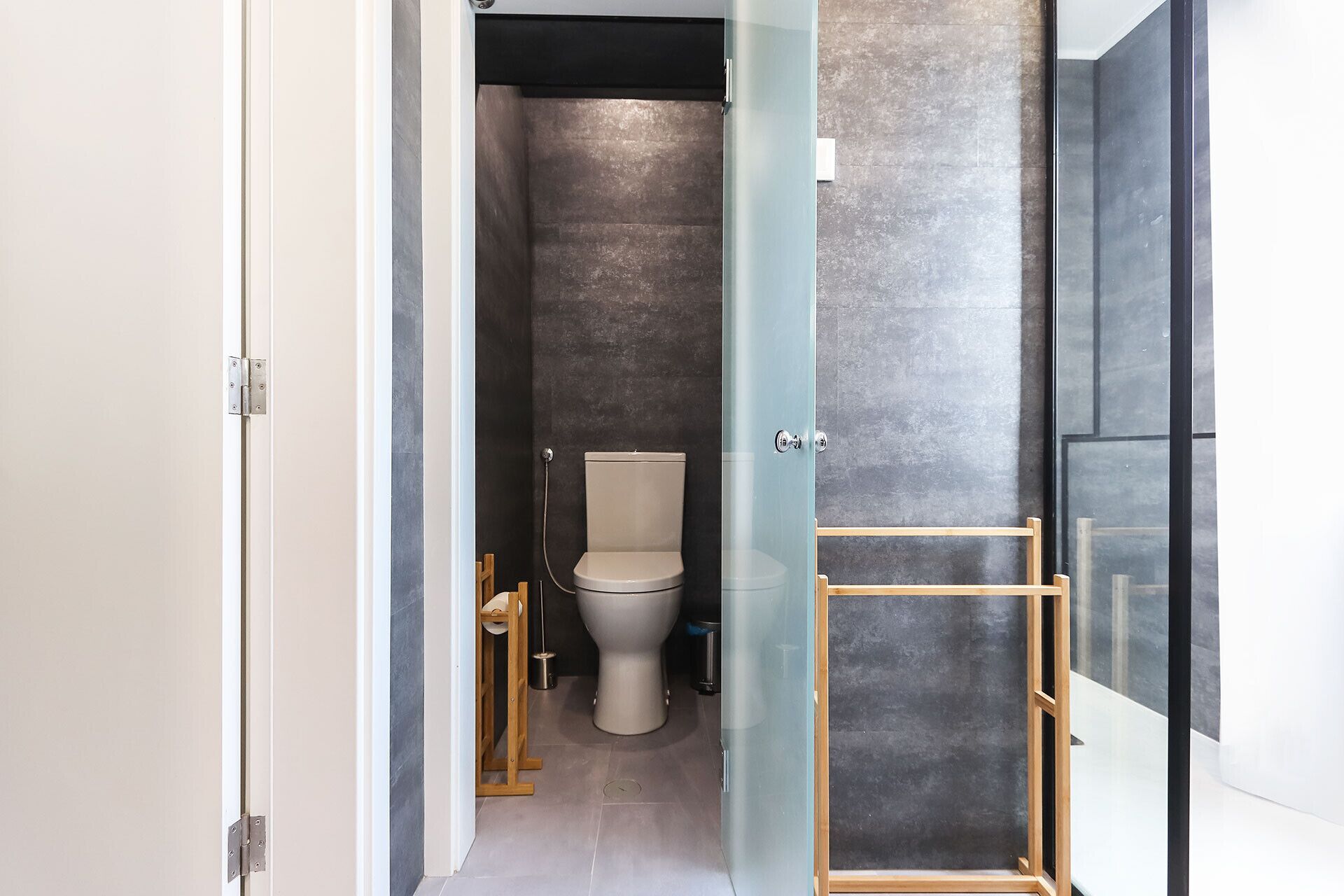A narrow hallway leading to a bathroom with a toilet and a shower area.