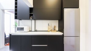 A modern kitchen with black cabinets, a white countertop, a microwave, and a stainless steel refrigerator. - Rato Design With Terrace By Homing (Lisbon)