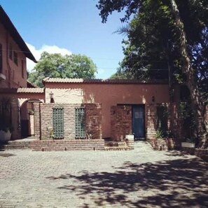 A brick building with a tiled roof, a door, and windows with green shutters. - Ferndale Lodge (Randburg)
