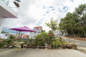 Relax in style on this serene patio, complete with a table, chairs, and lush greenery.