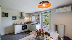 Cocina compacta con armarios blancos, microondas y estufa. Hay una mesa de comedor con platos, cubiertos y un florero con flores.