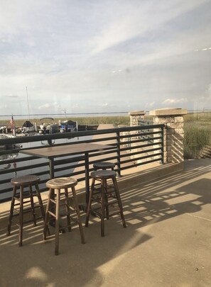 A patio with a table and stools overlooking a body of water with boats and an American flag. - Private home and entrance, stocked kitchen, fenced yard, Pets, boats ok,Parking  (St. Cloud)