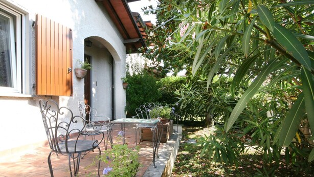An outdoor patio with a table and chairs, surrounded by plants and a wooden fence. - Wonderful private villa for 8 guests with WIFI, TV and terrace (Forte Dei Marmi)