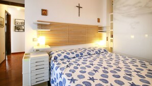 A bedroom with a wooden slat headboard, a bed with a blue and white patterned bedspread, a bedside table with a lamp, and a small cross on the wall. - Wonderful private villa for 8 guests with WIFI, TV and terrace (Forte Dei Marmi)