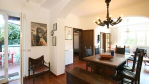 A dining area with a wooden table, chairs, and a chandelier. There is a door leading to another room and a view of the outside. - Wonderful private villa for 8 guests with WIFI, TV and terrace (Forte Dei Marmi)