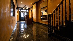 A polished hallway with a wooden staircase, a reception desk, and a mirrored wall. - The Hadley Hotel (Barnet)
