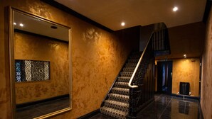 A polished lobby with a grand staircase, a large mirror, and a decorative wall panel. - The Hadley Hotel (Barnet)