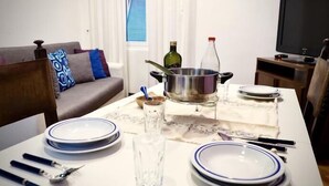 A dining area with a table set for four, including plates, cutlery, and a pot. A sofa and a TV are visible in the background. - Splendida Dimora Negri (Genoa)