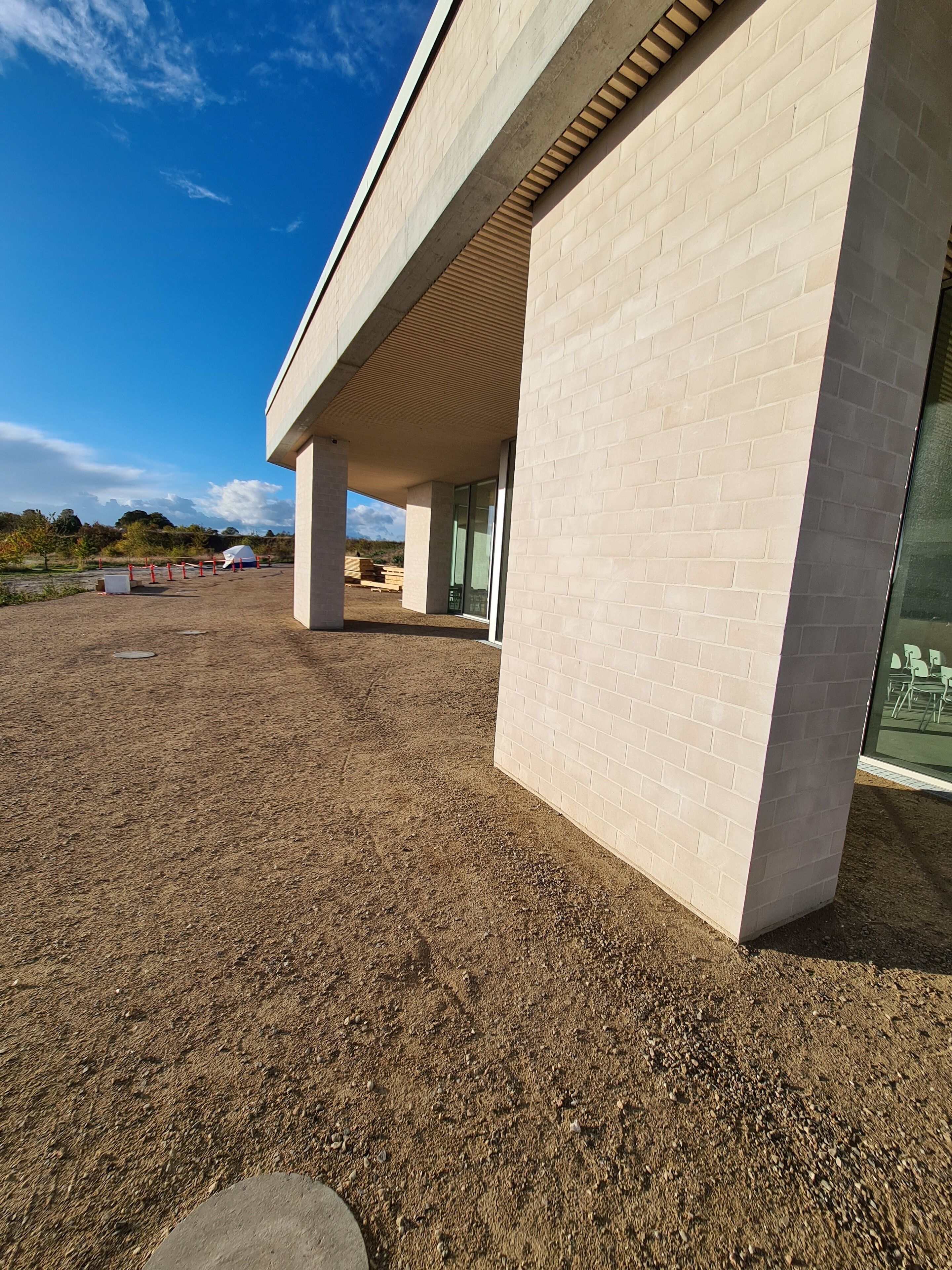 A modern building with a flat roof, large windows, and a paved area in front.