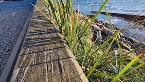 A wooden boardwalk with a view of the sea and distant land. - Danhostel Stevns (Store Heddinge)
