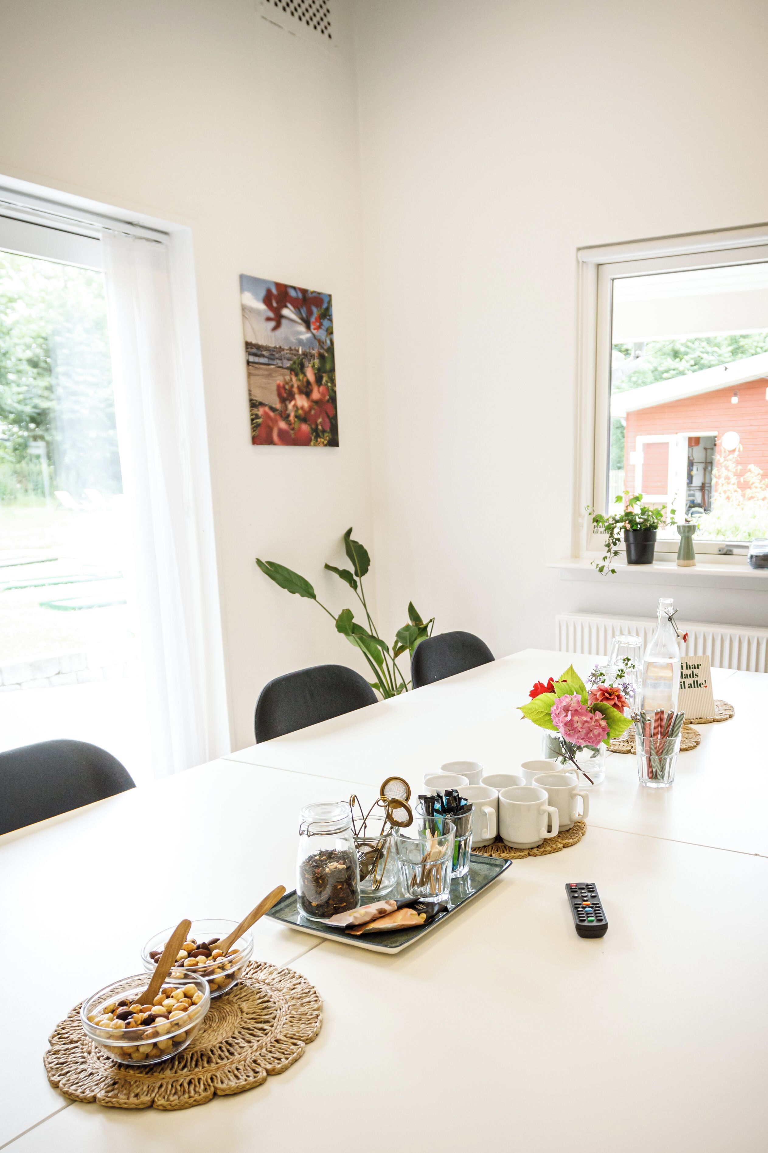 A dining table with a tray of snacks, a remote control, and a vase of flowers.