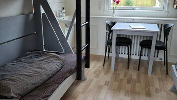Een stapelbed met bureau en stoelen in een kamer met een raam.