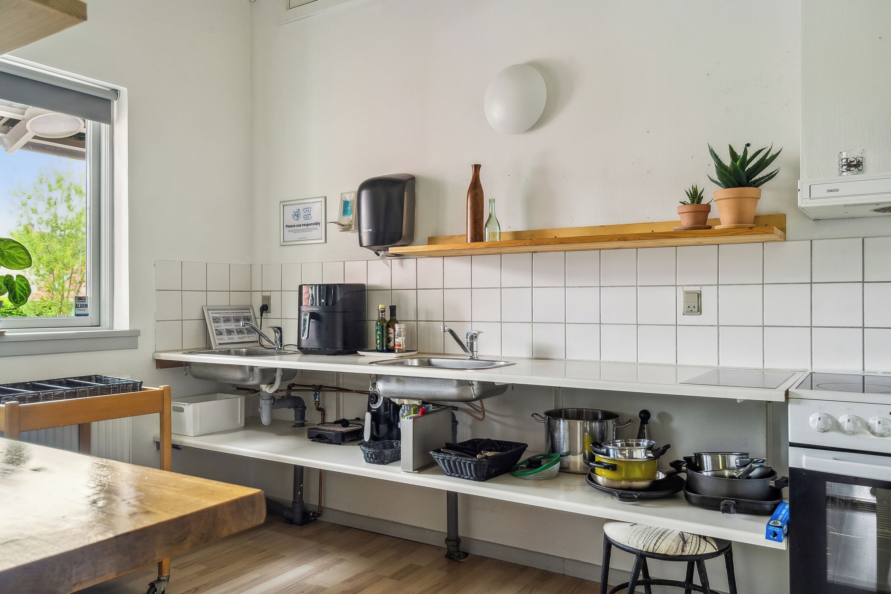 Una cocina con una mesa de madera, un fregadero, una estufa y diversos utensilios de cocina.