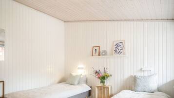 Une chambre avec deux lits, un plancher en bois et un plafond avec des poutres apparentes.