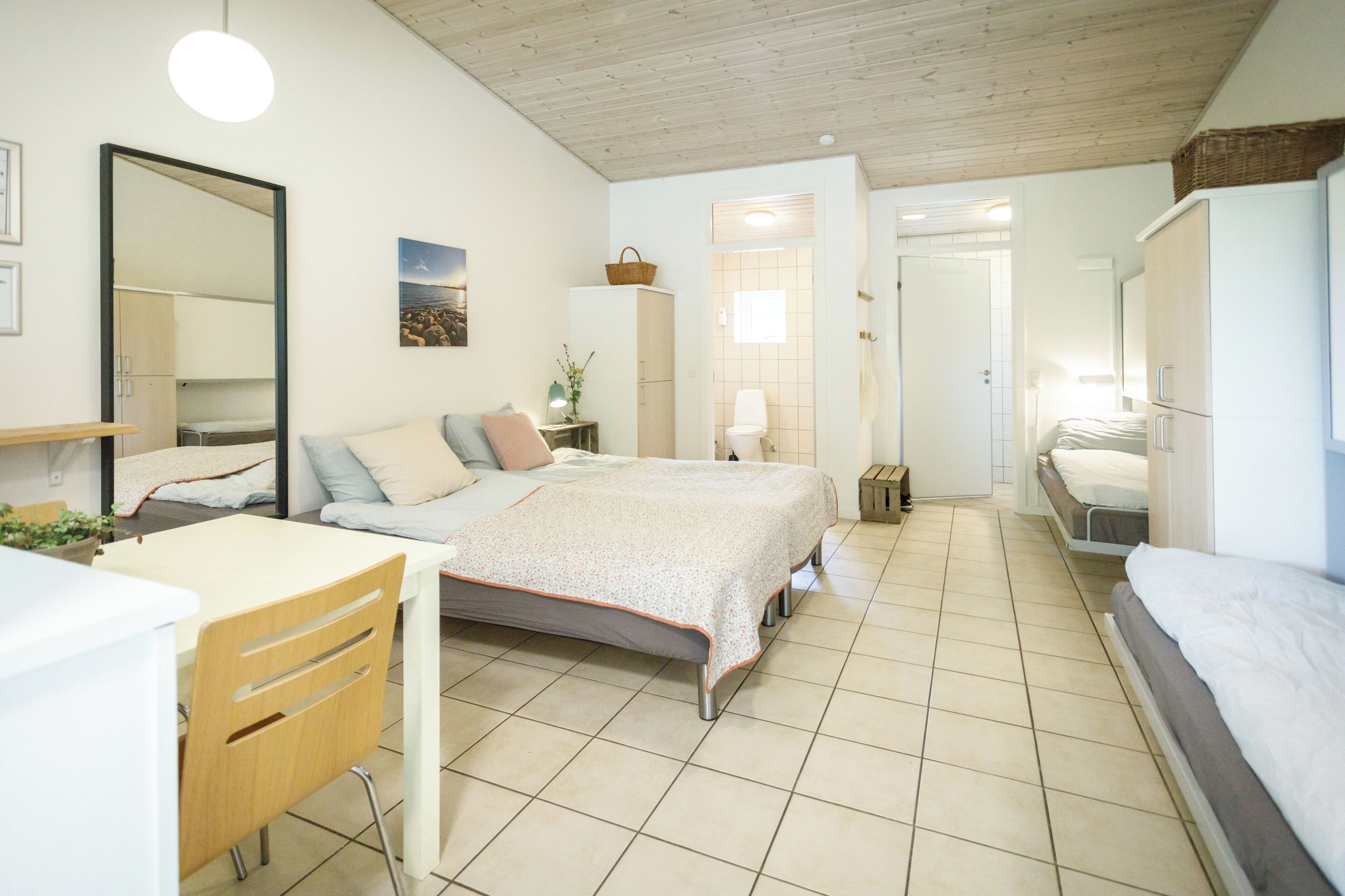 A bedroom with a bed, a desk, a chair, a wardrobe, and a bathroom.