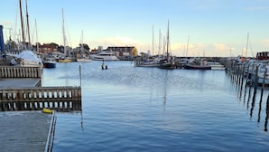 A marina with boats docked, a wooden pier, and large rocks in the foreground. - Danhostel Stevns (Store Heddinge)
