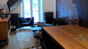Ein modernes Wohnzimmer mit einem Holzesstisch, einer Couch und einem großen abstrakten Gemälde an der Wand.