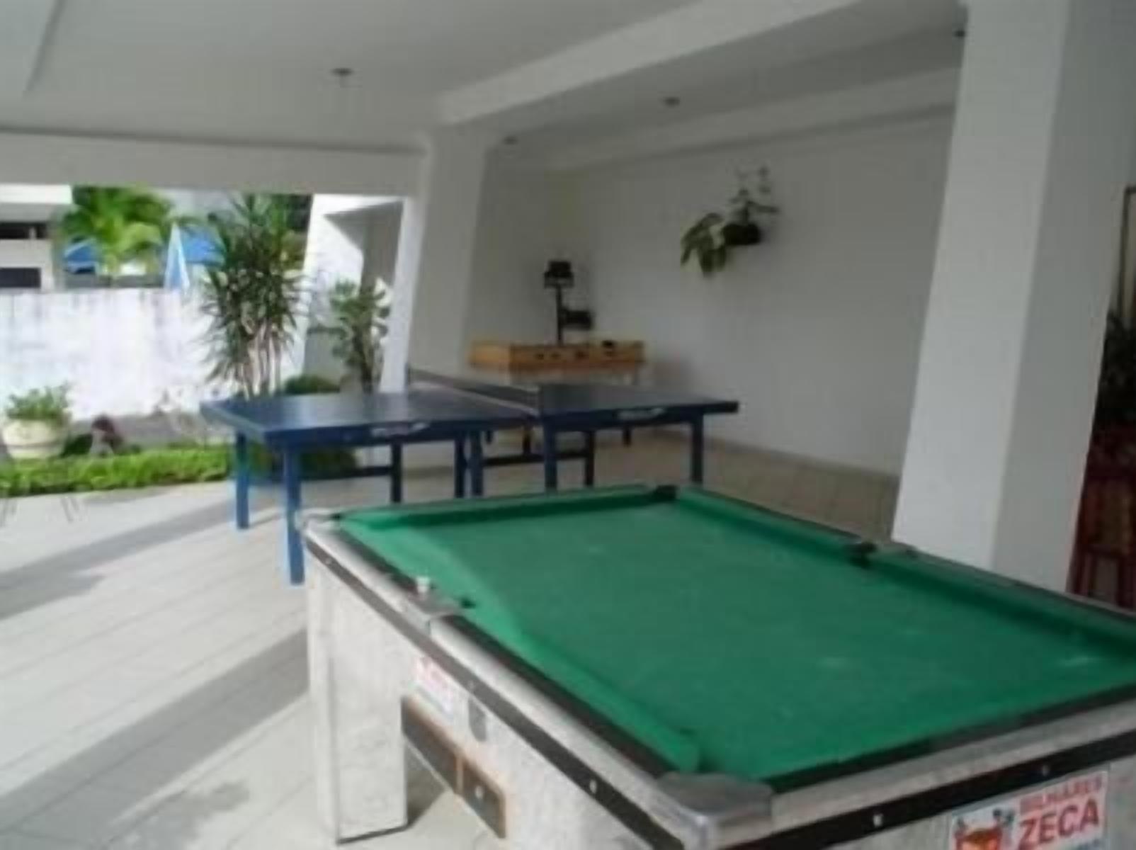 A pool table and a billiards table in a room with white walls and a tiled floor.