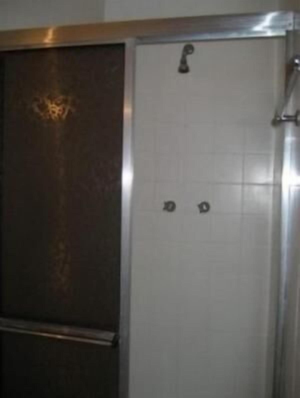A bathroom with a white tiled wall, a metal door, and a shower area.