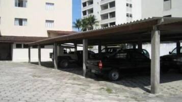 Een overdekte parkeerplaats met een gebouw op de achtergrond.
