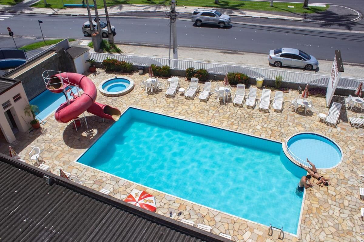 A rooftop swimming pool with a slide, lounge chairs, and a stone-tiled deck.