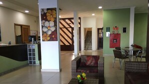A lobby with a reception desk, seating area, and a staircase.