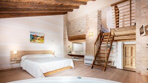 Un dormitorio con cama, una escalera de madera, un baño con bañera y una pared de ladrillo.