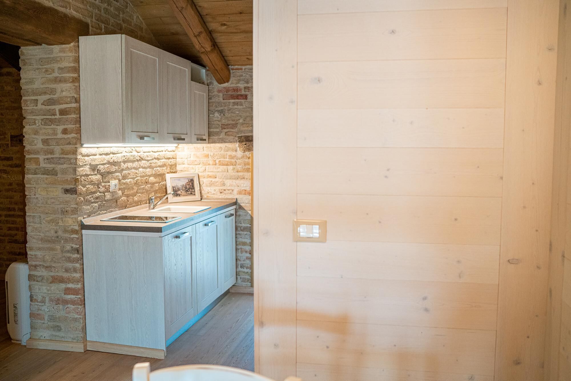 Una cocina con encimera de madera, un fregadero y armarios frente a una pared de ladrillo.