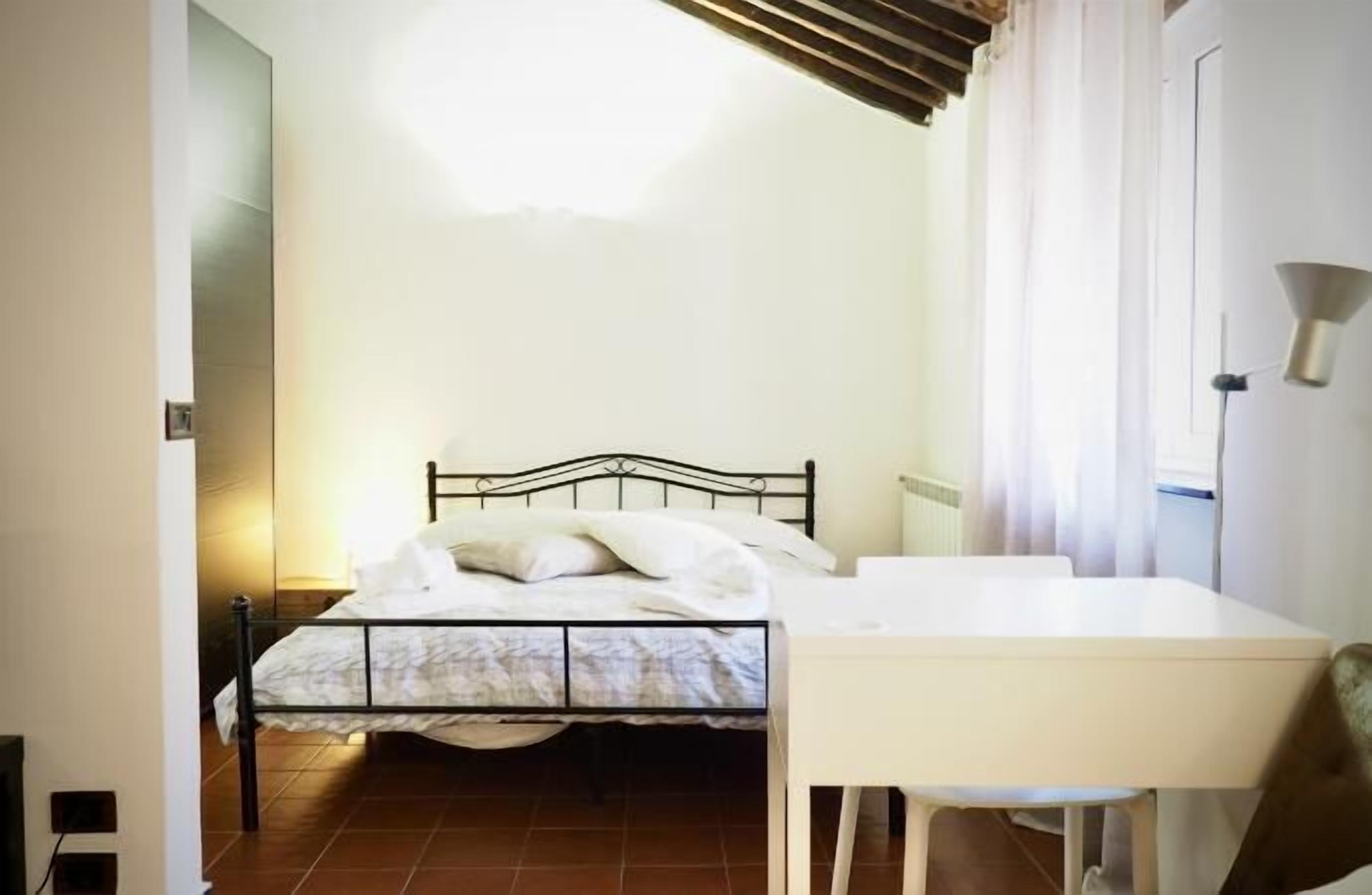 A bedroom with a bed, a bedside table, and a lamp.