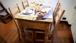 Una mesa de madera con sillas, una cesta de pan y una taza de café.
