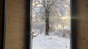 Une fenêtre donnant sur un paysage enneigé, avec des arbres et un banc.