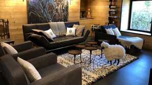 Un salon chaleureux avec un canapé en cuir noir, un chien blanc et duveteux, et un grand tableau abstrait accroché au mur.
