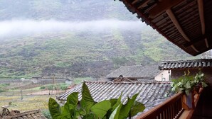 A traditional building with tiled roofs and a balcony with potted plants. - Homestay A San - Hostel (Meo Vac)