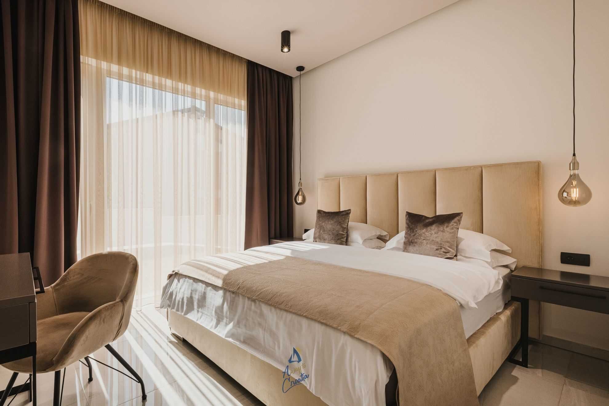 A hotel room with a bed, a desk, a chair, and a nightstand.