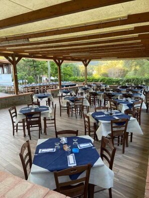 An outdoor dining area with multiple tables and chairs, covered by a wooden pergola. - Il Moro della Molpa (Centola)
