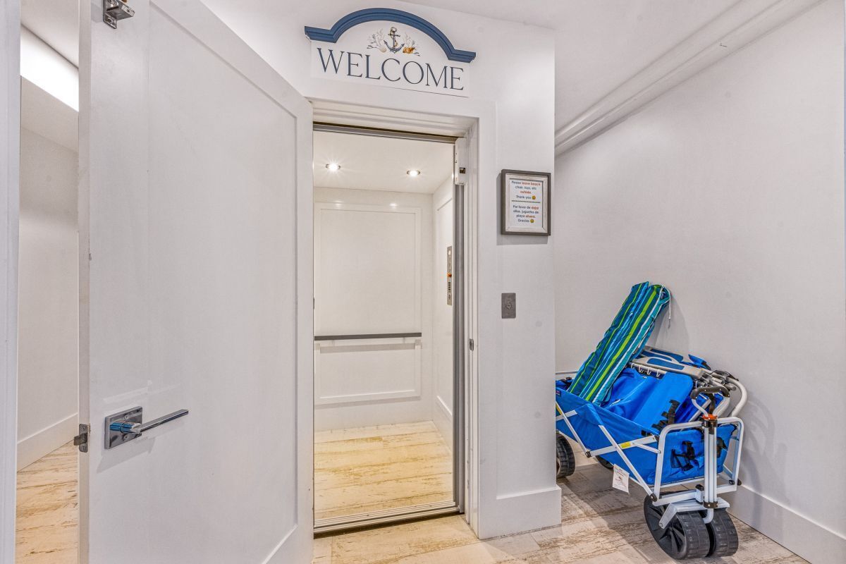 A hotel entrance with a 'WELCOME' sign, a luggage cart, and a framed notice on the wall.