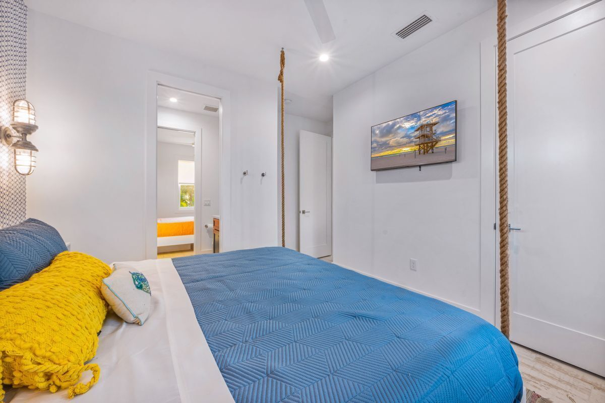 A bedroom with a large bed, a painting on the wall, and a door leading to another room.