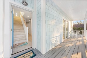 A wooden deck with a white railing, a welcome mat, and a staircase leading to a door. - Beachview Retreat: Steps to the beach, Gulf views! (Anna Maria)