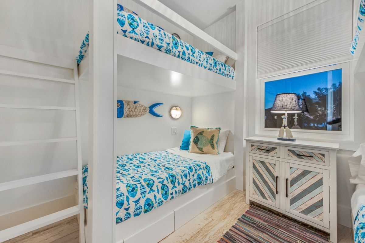Une chambre avec des lits superposés décorée sur le thème de la marine, avec une couvre-lit à motifs de poissons et des éléments décoratifs sur les murs.